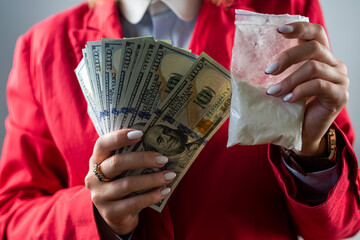 woman holding hundred dollar bill for each dose of cocaine drug and drugs in a bag. - obrazy, fototapety, plakaty