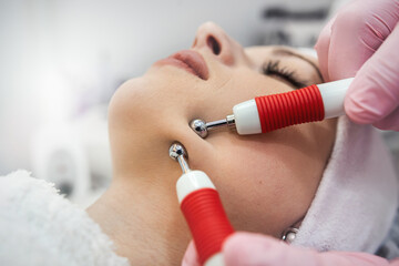 Cosmetologist makes hardware procedure for smoothing wrinkles on female face at spa