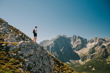 Embracing the beauty of the Belianske Tatras, a young traveler revels in serenity, all while the High Tatras' grandeur unfolds in the backdrop.