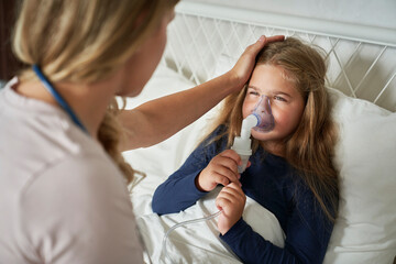 Pediatrician giving  nebulizer and taking care of an ill child at home