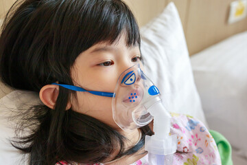 Sick little asian girl inhalation with nebulizer for respiratory treatment