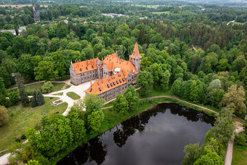 Cesvaine medieval castle in Latvia from above. Building of stones with a brown tiled roof. - obrazy, fototapety, plakaty