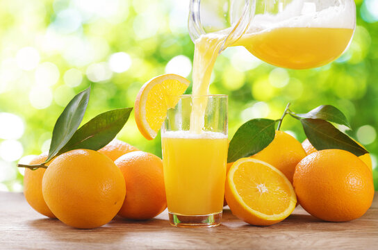 Orange juice pouring into glass. Glass of orange juice and fresh fruits