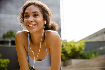 Smiling sportswoman resting while working out outdoors at street