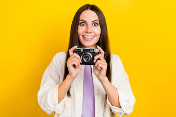Portrait of ecstatic astonished girl with long hairstyle wear white shirt hold camera make photo isolated on yellow color background