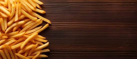 Fototapeten In Kyiv Ukraine there is a top view of French fries on a dark wooden background McDonald s Corporation is the largest fast food restaurant globally There is space for text © vxnaghiyev