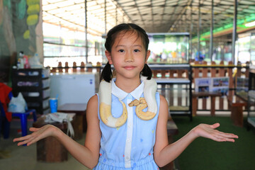 Portrait of Asian girl kid with pet snake or royal albino python on neck (Boa constrictor snake).