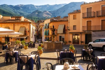 Selbstklebende Fototapeten Palermo Castelbuono, ITALY - August, 4, 2023. Fountain and cafes with tables in the small town square - piazza of Castelbuono, Sicily. Palermo Province, Madonie mountains on background.  © Olga
