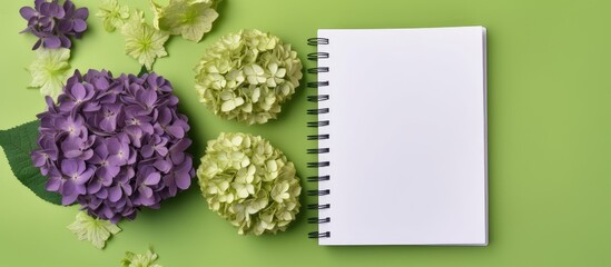 Purple background with dried hydrangea flowers on a green spiral notebook Copy space