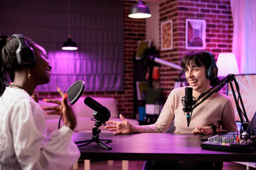 Online show host making guest laugh, cracking jokes during comedy focused podcast. Talking show...