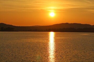 Naklejka premium Golden River Sunset Behind Majestic Mountains