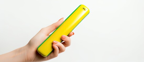 A yellow phone in a woman s hand with green nails white background Copy space - obrazy, fototapety, plakaty