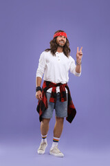 Stylish hippie man showing V-sign on violet background