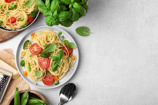 Delicious pasta primavera and ingredients on light gray table, flat lay. Space for text