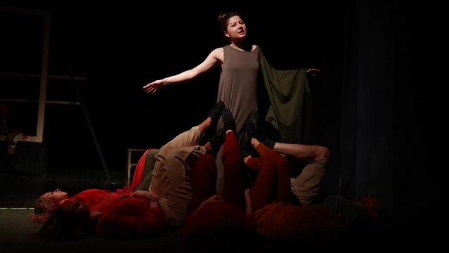 Actors and actresses perform a modern performance on the stage of the theater.	