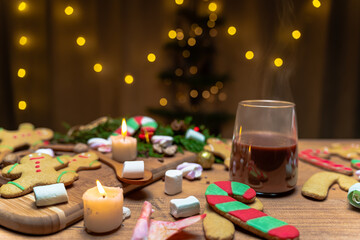 Christmas atmosphere with gingerbread cookies and candles on the table, steam rising from the hot chocolate.