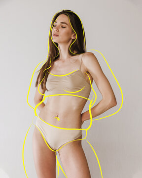 Portrait of posing fit girl in lingerie with drawn silhouette overweight woman around body against studio background. Health care.