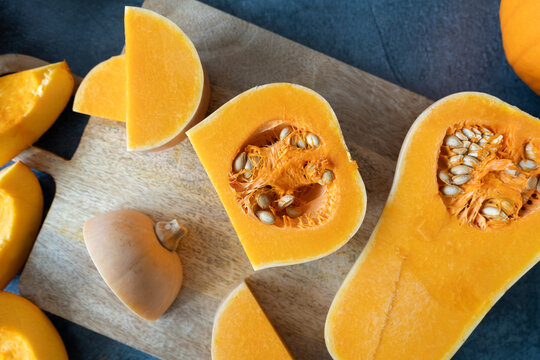 Sliced Butternut Squash And Kitchen Knife On A Wooden Board. Cutting Pumpkin Into Slices. Fresh Raw Sliced Pumpkins Pieces. Preparing Food Ingredients For A Seasonal Autumn Fall Dish, Soup Or Pie.