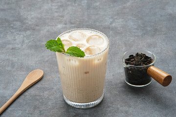 Milk tea with brown sugar syrup in a tall glass with ice and mint leaf