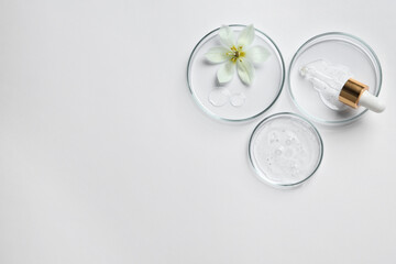 Petri dishes with samples of cosmetic oil, pipette and beautiful flower on white background, flat...