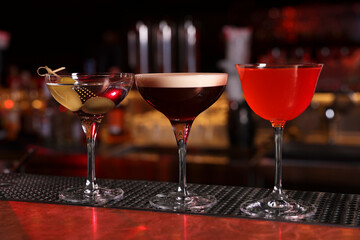 Glasses of different Martini cocktails on bar counter