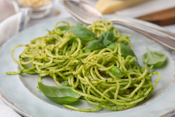 Delicious pasta with pesto sauce and basil on plate, closeup