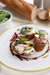 Delicious bruschettas with cream cheese, vegetables and balsamic vinegar on table, closeup