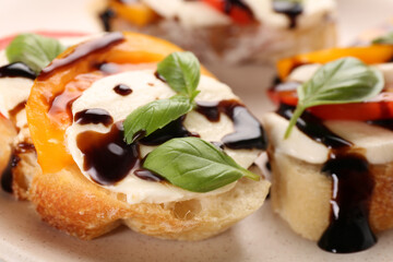 Delicious bruschettas with mozzarella cheese, tomatoes and balsamic vinegar on beige plate, closeup