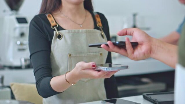 Barista using phone and easy payment in the coffee shop.