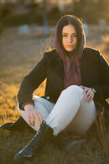 A woman in a hoodie looking at the camera during sunset 