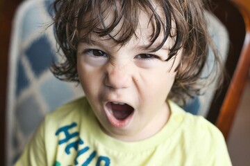 Closeup headshot portrait of a young white Caucasian boy throwing a temper tantrum, looking...