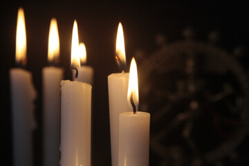 Lit white candles in the dark with blurry Kali goddess statue