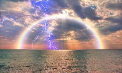 Calm sea before storm with amazing rainbow and lightning at sunset   