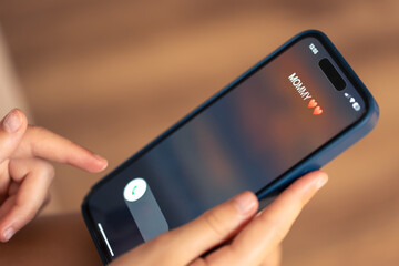 Smartphone in child hands with Incoming Mommy call on a screen.