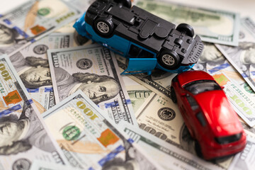 Accident between two toy cars on the background of dollar bills