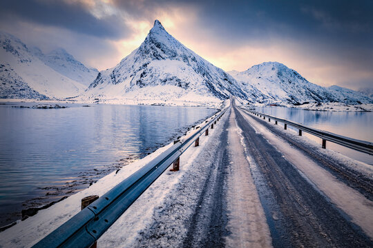 Dramatic winter sunrise onf Lofoten Islands with Volandstind peak on background. Splendid morning scene of Norway with Fredvang bridge. Over polar circle landscape. Traveling concept background.