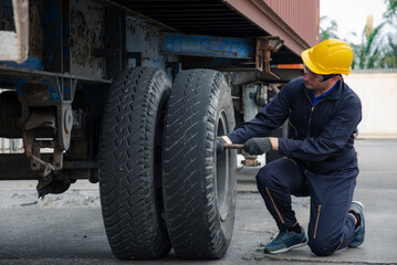 Fototapeta na wymiar Man in tights change wheels on the container yard , a man wearing jumpsuit Changing the wheels of a container tractor at the container yard.