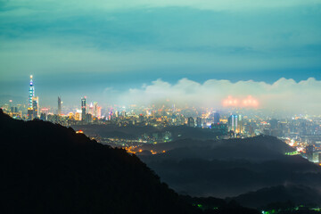Fototapeta na wymiar Nocturnal Marvel: City Lights and Shifting Cloudscape from the Summit. View of the urban landscape from Dajianshan Mountain, New Taipei City, Taiwan.