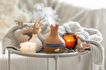 Aroma composition with a modern aroma oil diffuser and a knitted element.