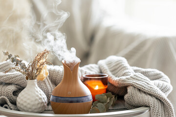Aroma composition with a modern aroma oil diffuser and a knitted element.