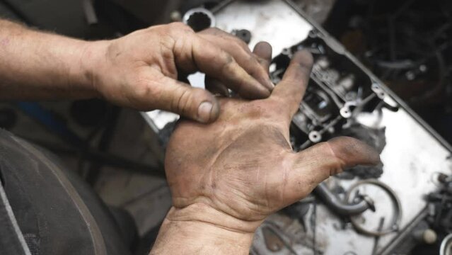 POV male dirty hands of young mechanic at workshop. Repairman rubbing unclean arms from fuel oil after hard work at garage. Concept of maintenance service. Slow motion