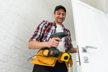Man remove the door. Twists self-tapping screw with a screwdriver. Stainless door hinges on a white...