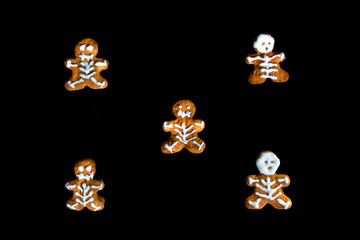 A group of baked gingerbread men on black background. Halloween Gingerbread Cookies on black background, selective focus, and blank space. creative Halloween background. Top view