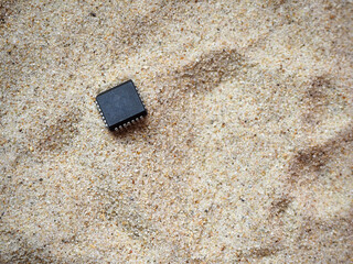 Microchip buried in the sand. Semiconductor industry, processor manufacturing concept background.