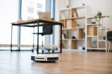 Robot vacuum cleaner handling debris on bare floor in office