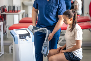 Doctor using machine to treat the knee joints of a patient.