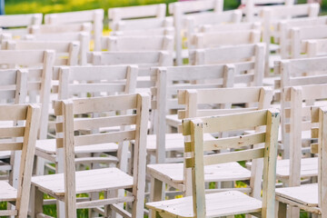 Elegant Garden Celebration: White chairs arranged on the lush green grass create a charming wedding ceremony setting amidst nature's backdrop.