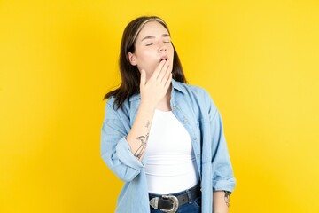 Young beautiful woman wearing denim overshirt being tired and yawning after spending all day at...