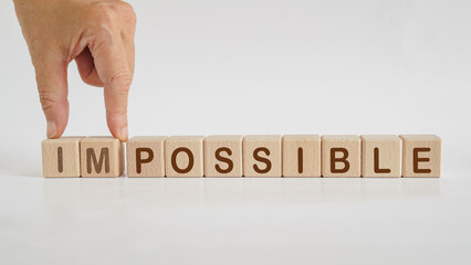 hand separated impossible to possible word on wooden cube block isolated background. For positive thinking, business strategy, enthusiastic, mindset concept