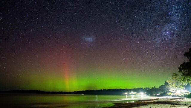 aurora australis taking on a sandy beach in a beach town in tasmania australia